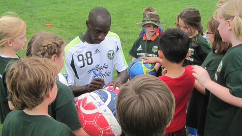 Defender Futty Danso signs autographs following coaching at a youth soccer camp.
