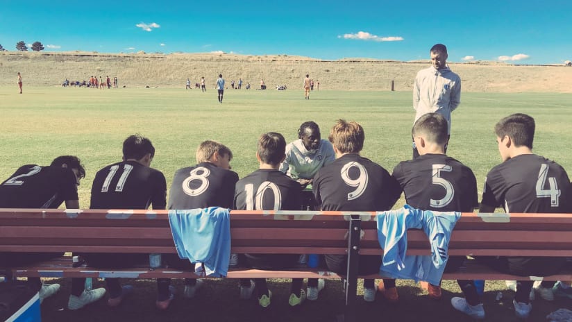 Rumba Munthali talking to Sporting KC Academy players on the bench
