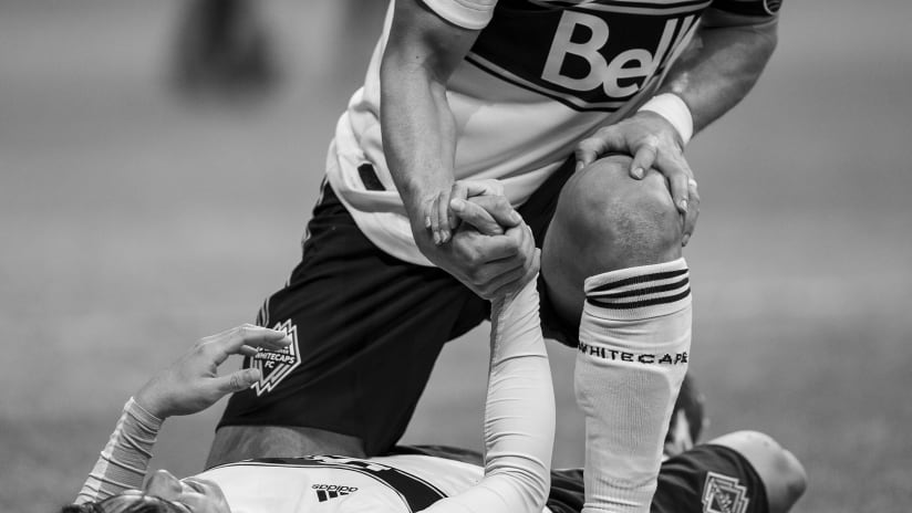 Epic black and white photo - pulling teammate off pitch