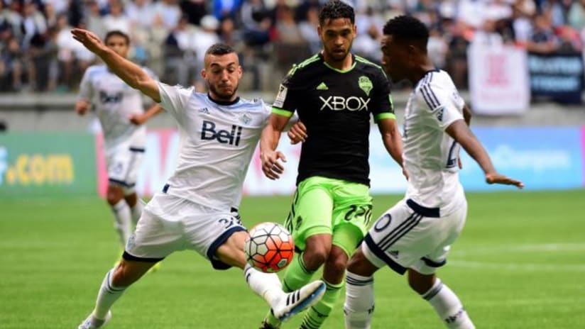Russell Teibert and Deybi Flores (Vancouver Whitecaps) attempt to block Lamar Neagle (Seattle Sounders)