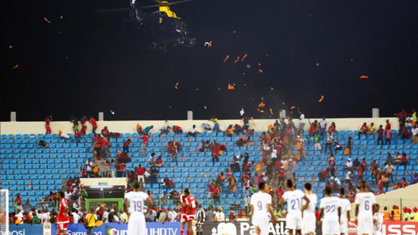 Ghana and Equatorial Guinea players look up at a helicopter during a crowd disturbance at AFCON