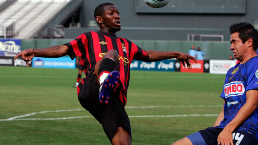 Man City's Shaun Wright-Phillips taps the ball over an America defender.