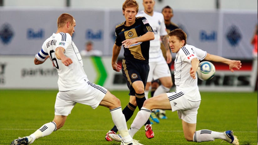Philadelphia's Brian Carroll fires off a shot between Vancouver's Jay DeMerit and Terry Dunfield.