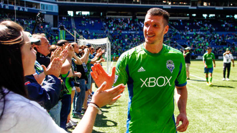 Seattle Sounders forward Kenny Cooper gives a high five to some fans