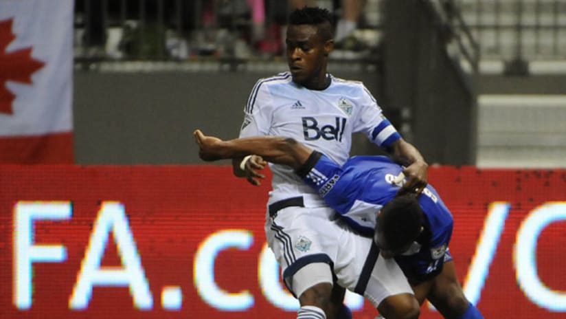 Vancouver Whitecaps midfielder Gershon Koffie wrestles with an FC Edmonton player