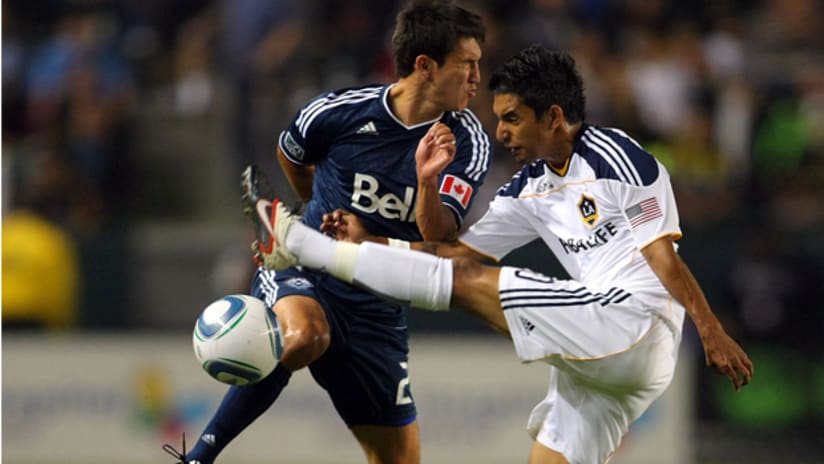 A.J. DeLaGarza #20 of the Los Angeles Galaxy clears the ball under pressure from Shea Salinas #22 of the Vancouver Whitecaps