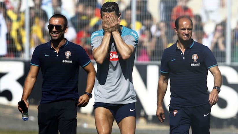 Cristiano Ronaldo covers his face as he walks off the field in a World Cup training session