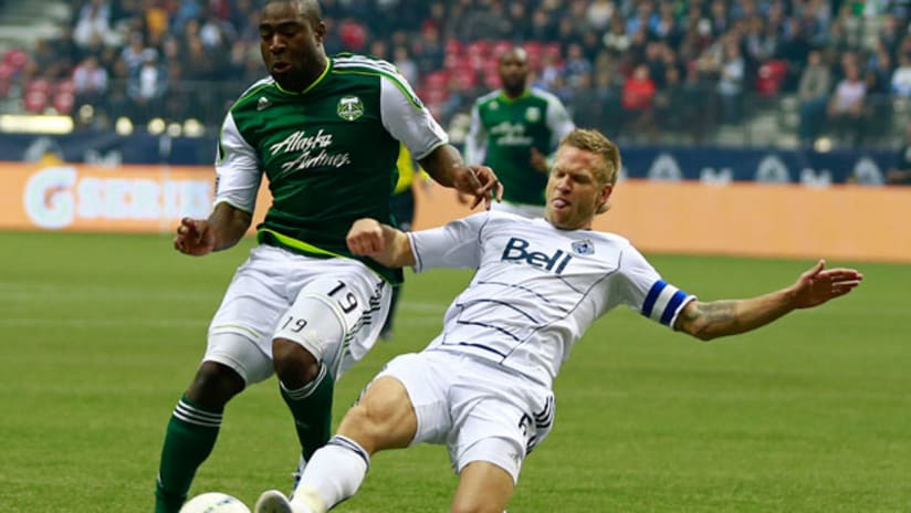 Vancouver's Jay DeMerit slides in to tackle Portland's Bright Dike.