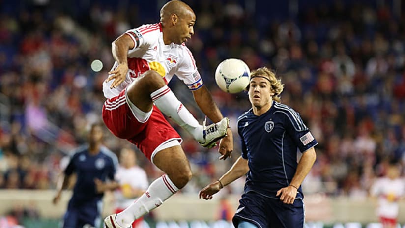 New York's Thierry Henry collects a ball under pressure from Sporting KC's Chance Myers.