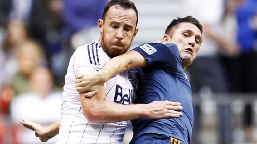 Vancouver Whitecaps' Andy O'Brien tussles with LA Galaxy's Robbie Keane.