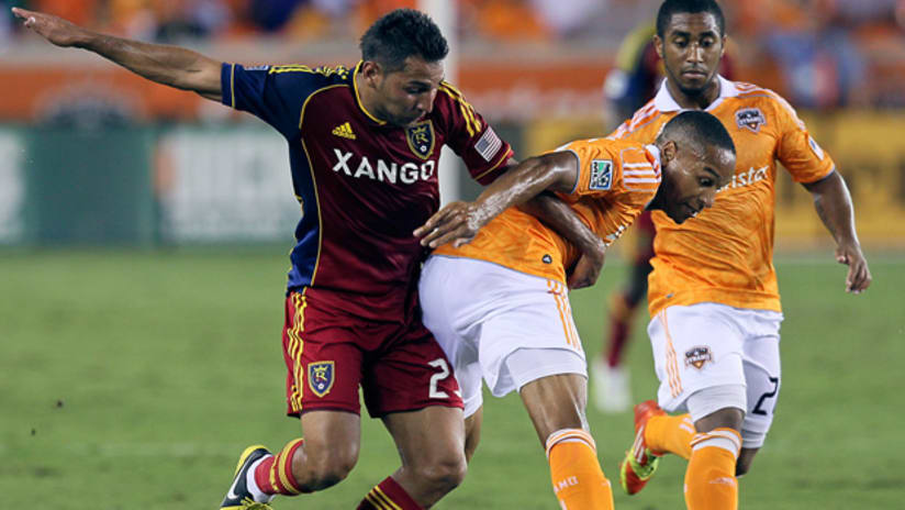 Houston's Ricardo Clark (center) takes the ball away from RSL's Paulo Jr. as Corey Ashe watches on.
