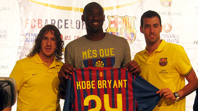 Kobe Bryant (center) holds a Barcelona jersey with players Carles Puyol (left) and Sergio Busquets.