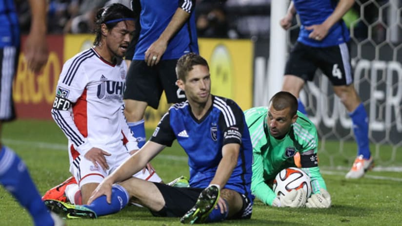 San Jose's Jon Busch makes a save in front of Clarence Goodson as New England's Daigo Kobayashi looks on