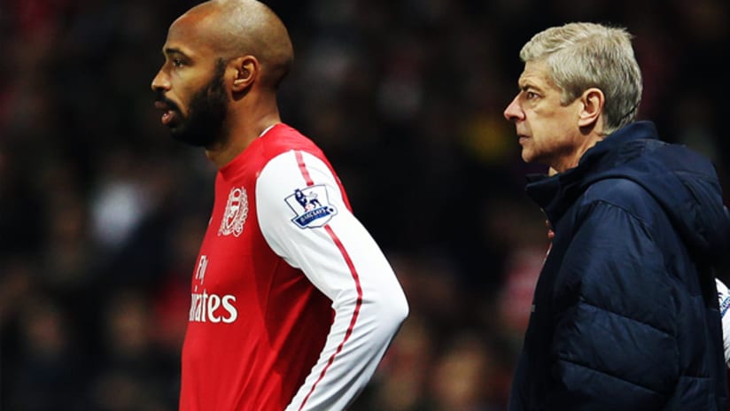 Thierry Henry stands in front of Arsenal head coach Arsene Wenger