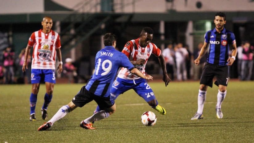 A Heredia player dribbles by Blake Smith in CCL play