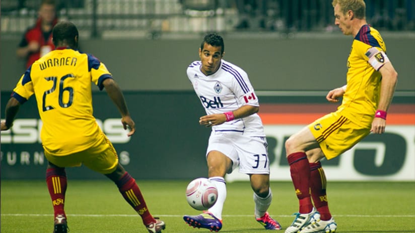 Vancouver's Camilo sends a pass between RSL defenders Collen Warner and Nat Borchers