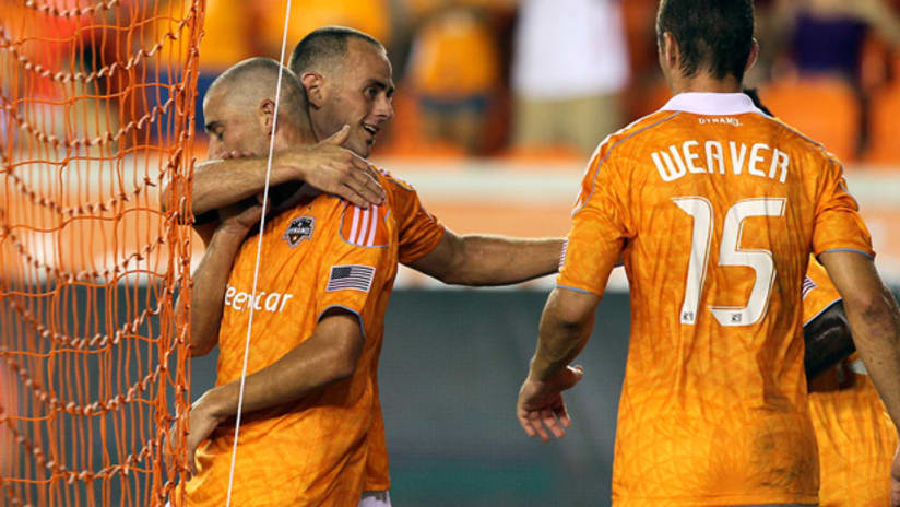 Houston's Colin Clark (left) is hugged by teammate Brad Davis as Cam Weaver watches on after scoring against RSL.