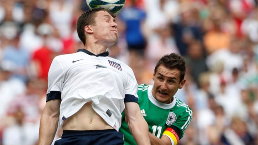 Matt Besler heads the ball away from Miroslav Klose