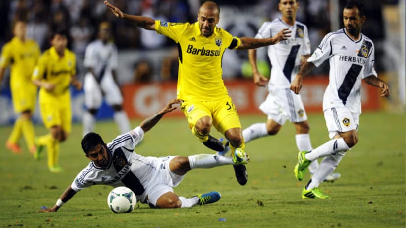 Columbus Crew's Federico Higuain skips over LA Galaxy's AJ DeLaGarza.