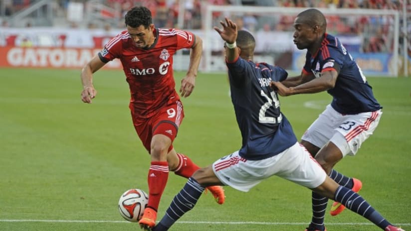 Toronto FC's Gilberto is surrounded by New England Revolution defenders