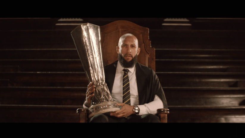 Tim Howard in Western Union ad, holding Europa League trophy