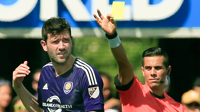 Luke Boden - Orlando City - receiving a yellow card from referee Armando Villarreal