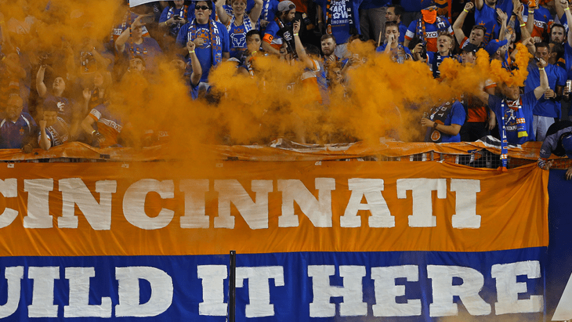 FC Cincinnati - fans with orange smoke, 'Build it here' sign