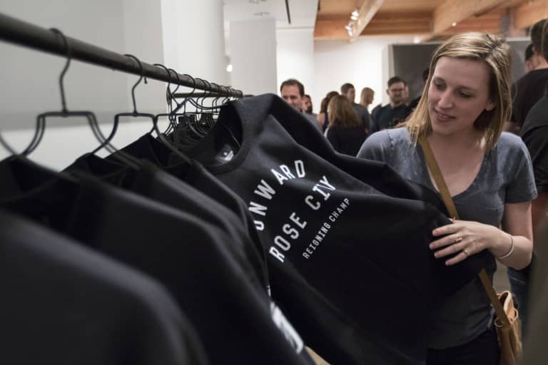 Reigning Champ unveils Portland Timbers capsule collection at party in the Pearl District - https://league-mp7static.mlsdigital.net/images/womanlookingatTimberssweatshirt.JPG?null