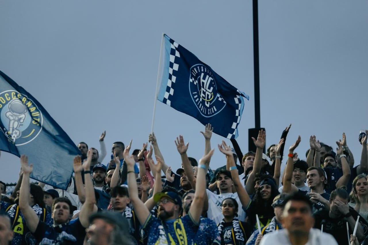 Fans in attendance celebrate Huntsville City FC's win over Crown Legacy FC during the inaugural game at Wicks Family Field at Joe Davis Stadium