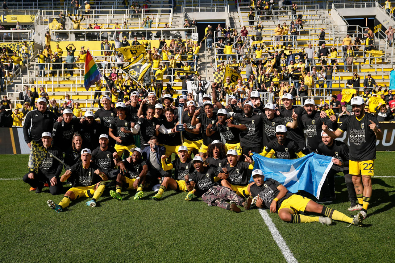 Crew 2 players and head coach Laurent Courtois pose with the trophy and fans for a picture after winning the MLS NEXT Pro Cup